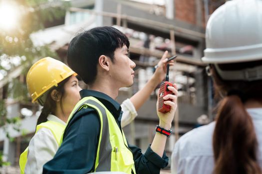 engineering and construction managers discussing project blue print on the table at construction site.