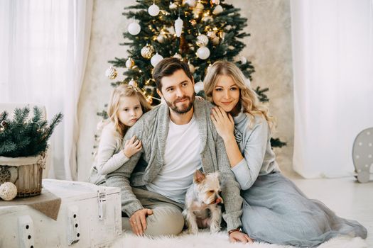 Happy family: mom, dad and pet. Family in a bright New Year's interior with a Christmas tree.