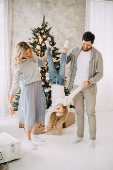 Happy family: mom, dad and pet. Family in a bright New Year's interior with a Christmas tree.