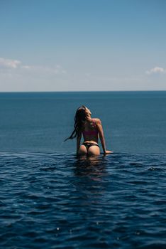 Happy woman in swimsuit swimming in infinity pool at luxury hotel against seafront. Relaxing, summer, travel, holiday, vacation and weekend concept