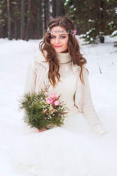 Beautiful bride in a white dress with a bouquet in a snow-covered winter forest. Portrait of the bride in nature.Beautiful bride in a white dress with a bouquet in a snow-covered winter forest. Portrait of the bride in nature.