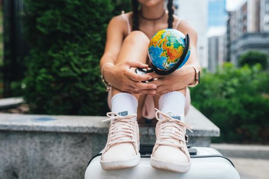 A beautiful young woman holds a small globe in her hands. Lifestyle and travel Concept