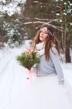 Beautiful bride in a white dress with a bouquet in a snow-covered winter forest. Portrait of the bride in nature.Beautiful bride in a white dress with a bouquet in a snow-covered winter forest. Portrait of the bride in nature.