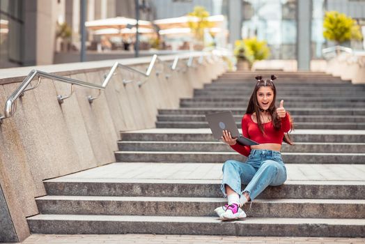 Beautiful young woman on the street and working using computer laptop