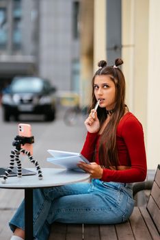 Young woman in a summer cafe doing remote work. Freelancer woman. Small business