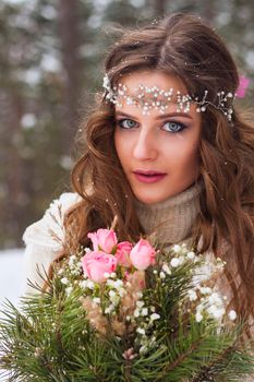 Beautiful bride in a white dress with a bouquet in a snow-covered winter forest. Portrait of the bride in nature.Beautiful bride in a white dress with a bouquet in a snow-covered winter forest. Portrait of the bride in nature.