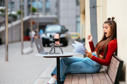 Young woman in a summer cafe doing remote work. Freelancer woman. Small business