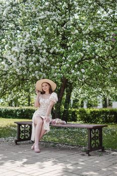 An attractive long-haired woman walks in the spring in the park of blooming apple trees. Spring portrait of a woman