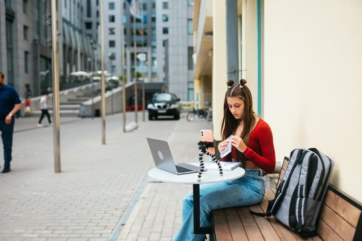 Young woman in a summer cafe doing remote work. Freelancer woman. Small business