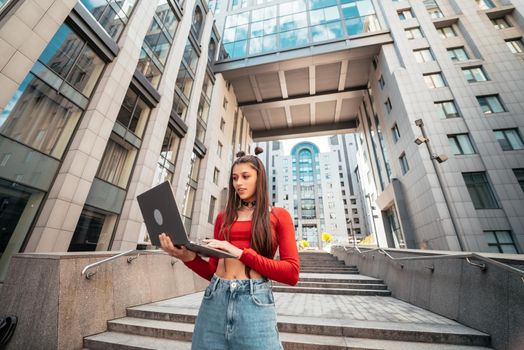 Beautiful young woman on the street and working using computer laptop