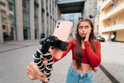 Young female blogger with smartphone streaming on the street. Close view
