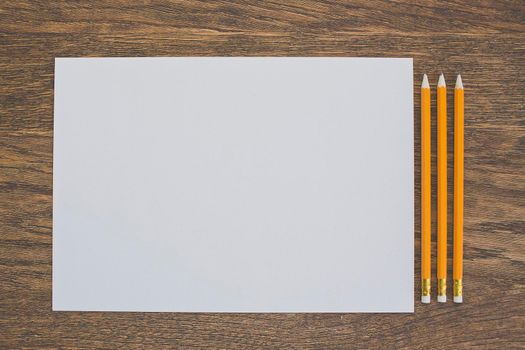 Paper and pencils on the wooden table. close-up.