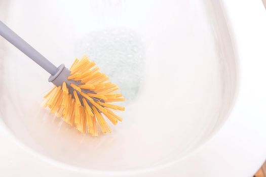 gray brush for cleaning and cleaning the toilet close-up. White toilet bowl, sanitary ceramics. The concept of cleaning agent, hygiene and disinfection of the bathroom at home and in public places