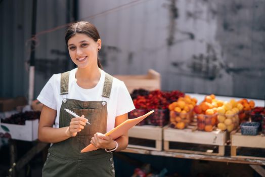 A woman seller of fruit at the market near the counter with fresh goods
