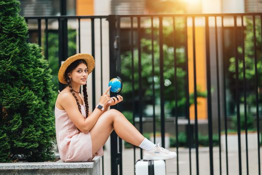 A beautiful young woman holds a small globe in her hands. Lifestyle and travel Concept