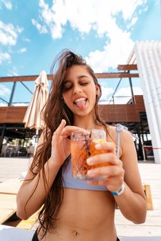 Pretty woman in bikini drinking cocktail at pool.