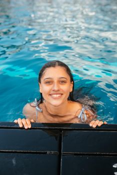Beautiful young woman resting on the edge of swimming pool