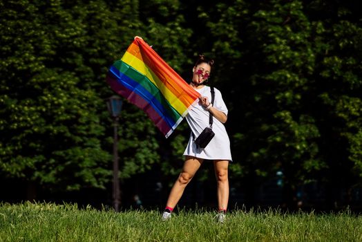 Young woman with lgbt pride flag in the park.