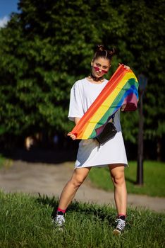Young woman with lgbt pride flag in the park.