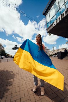 Young woman with national flag of Ukraine walking in the city