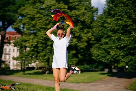 Young woman with lgbt pride flag walking in the park.