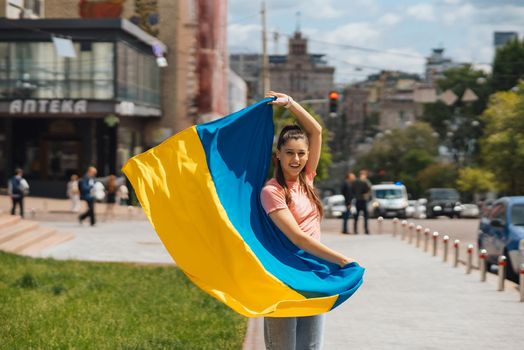 Young woman with national flag of Ukraine walking in the city
