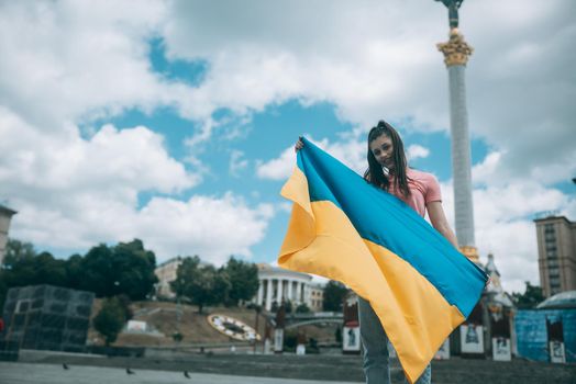 Young woman holding national flag of Ukraine in the city