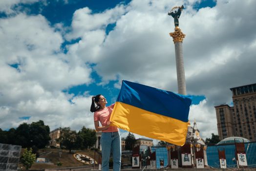 Young woman holding national flag of Ukraine in the city