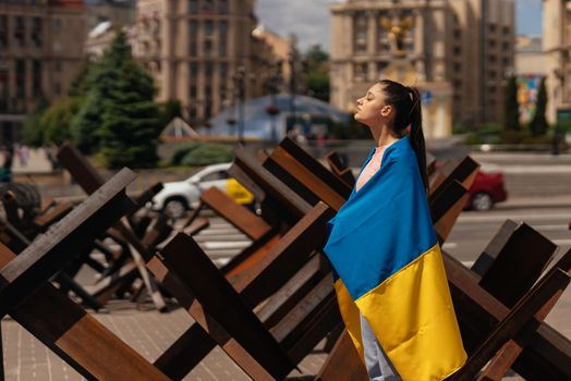 Young woman with national flag of Ukraine walking in the city