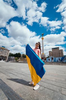 Young woman with national flag of Ukraine walking in the city
