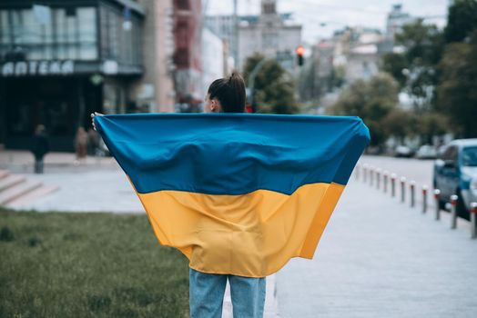 Young woman with national flag of Ukraine walking in the city