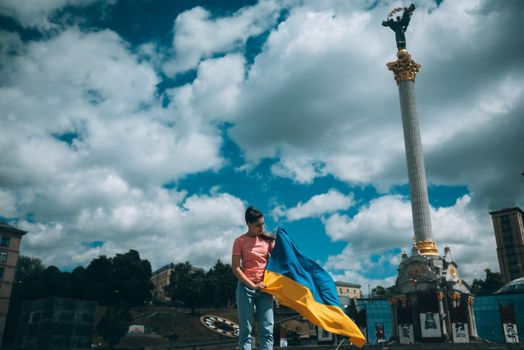 Young woman holding national flag of Ukraine in the city