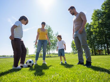 Happy family with two children play soccer in their leisure time