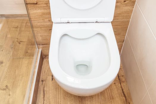 Clean, white ceramic toilet in the bathroom, toilet room. Open toilet with lid. Plumbing, mockup, design template for interior, cleaning, hygiene concept. View from above. Bathroom interior
