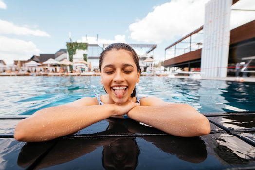 Beautiful young woman resting on the edge of swimming pool