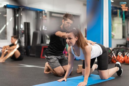 A female trainee exercises while being coached by her personal trainer at the crossfit box