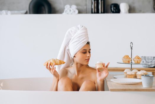 Fashion woman in the morning lying in the bath having breakfast