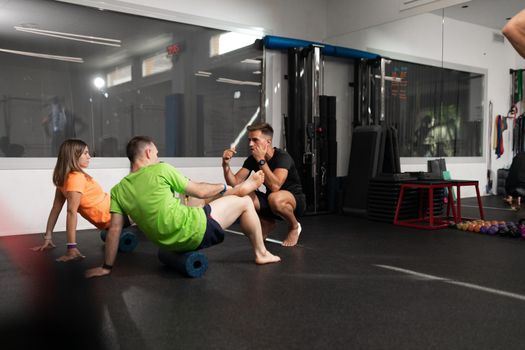 A coach guiding two of his trainees during a training session at the crossfit box