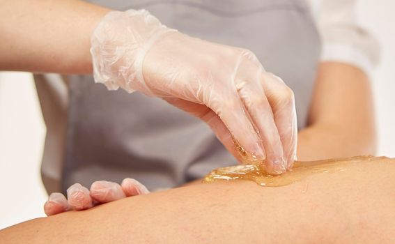 Sugar paste for light depilation. Depilation with sugar paste in the salon on a white background.