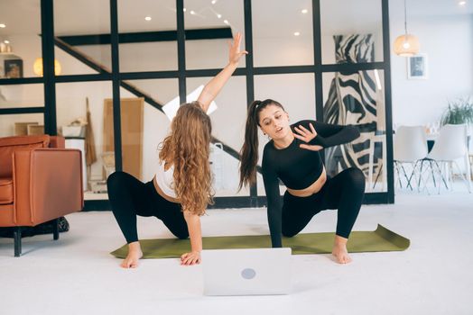 Two girls practice yoga at home