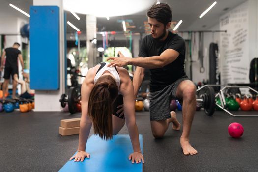 A coach correcting the posture of a female trainee during a training session at the gym