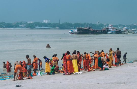 Pilgrim People are taking bath at the riverbank of the Ganges or river Hooghly . Babu Ghat, Kolkata, West Bengal, India. August 2, 2022