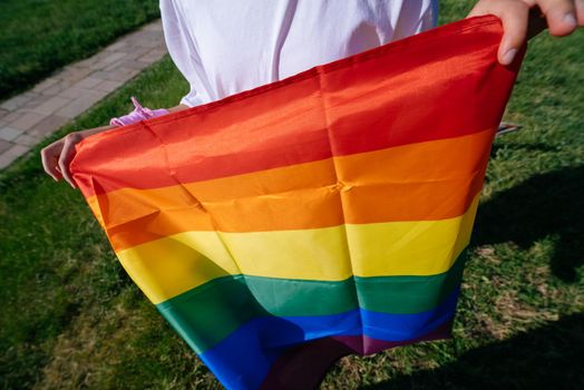 Young woman holding an LGBT pride flag in her hands. Close view, cropped photo