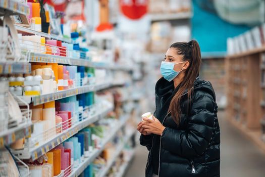 Young woman with face mask buying in the supermarket