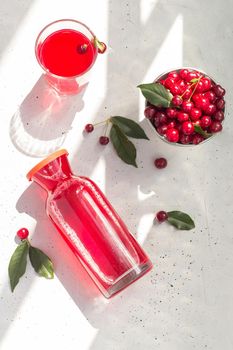 Cold cherry juice in a glass and bottle with ripe berries. Top view, The concept of summer refreshing drink morse or kompot.