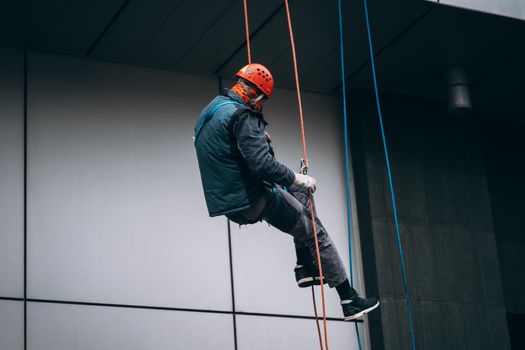 Industrial climber in uniform and helmet rises. Outdoor