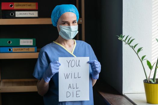 Female Doctor Showing Bad Prediction, Woman In Protective Mask With Sarcastic Look In Eyes Holding Poster That Says YOU WILL ALL DIE, Pandemic Concept