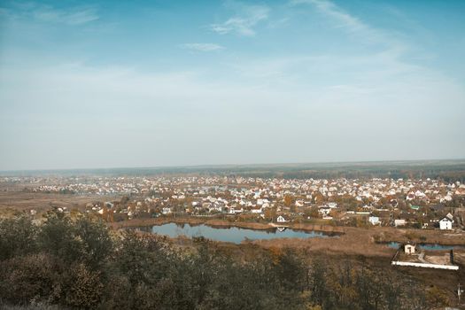 Modern cottage town or urban-type village on the lake. Rural panoramic landscape against the blue sky. Shot from the mountain. High angle view.