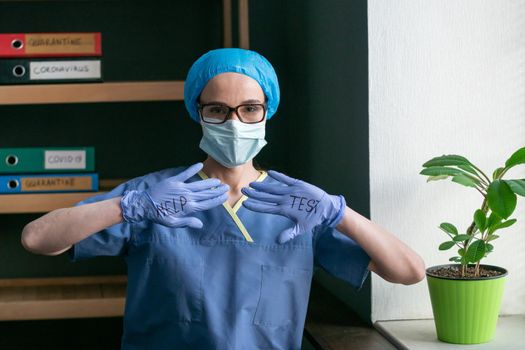 Help Test Sign From Female Doctor, Young Woman Wearing Medical Uniform With Disposable Cap And Mask, Shows Her Hands In Disposable Gloves With HELP TEST Sign On Both Of Them