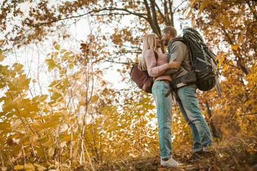 Young Traveler's Family Stopped In A Multicolor Autumn Forest, A Guy And A Girl Stand Facing Each Other, Hugging And Rejoicing In The Beauty Of Nature